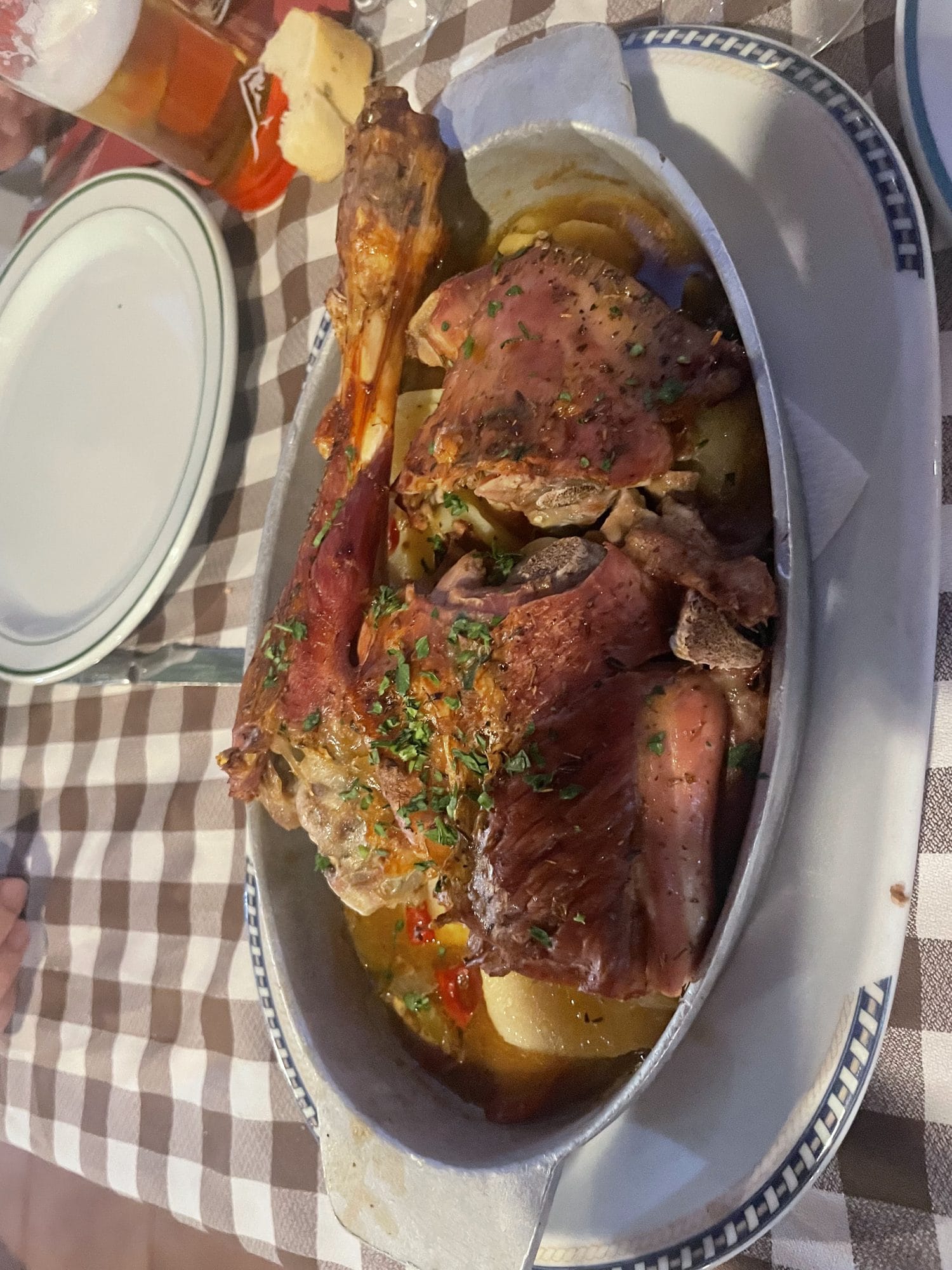 A roast with potatoes on a checked tablecloth