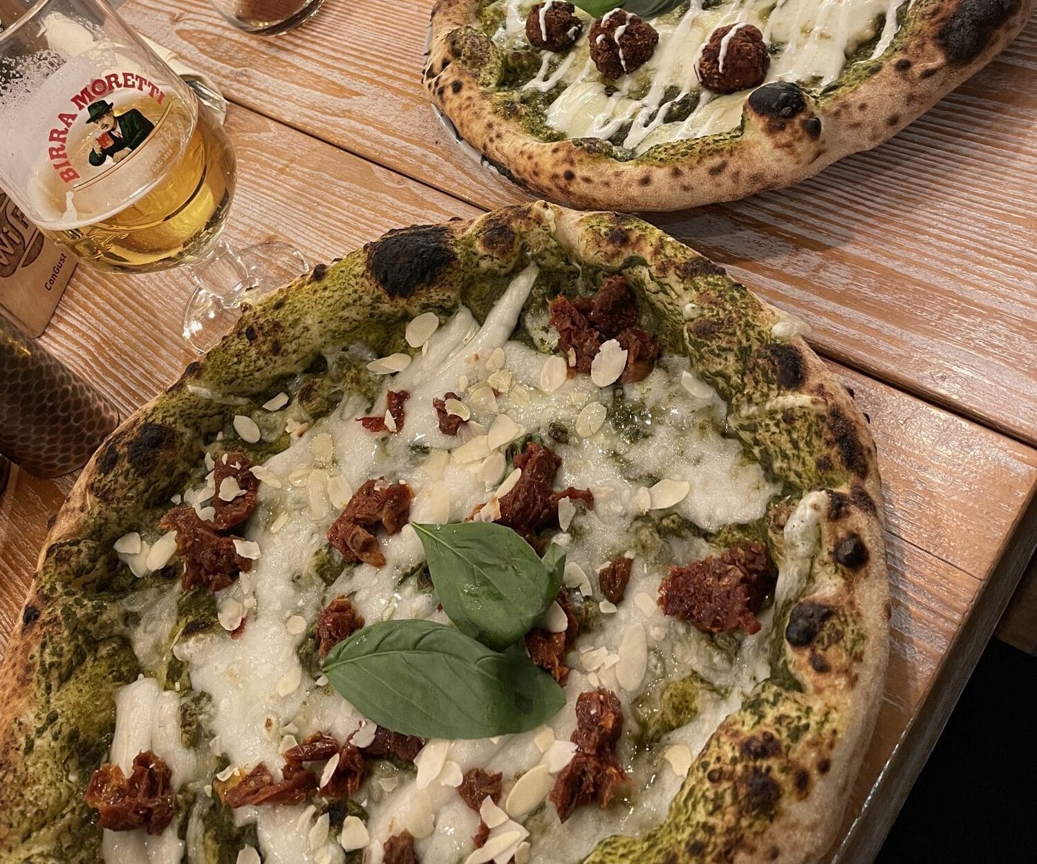 Pizzas with pistachio pesto and a margherita on a wooden table