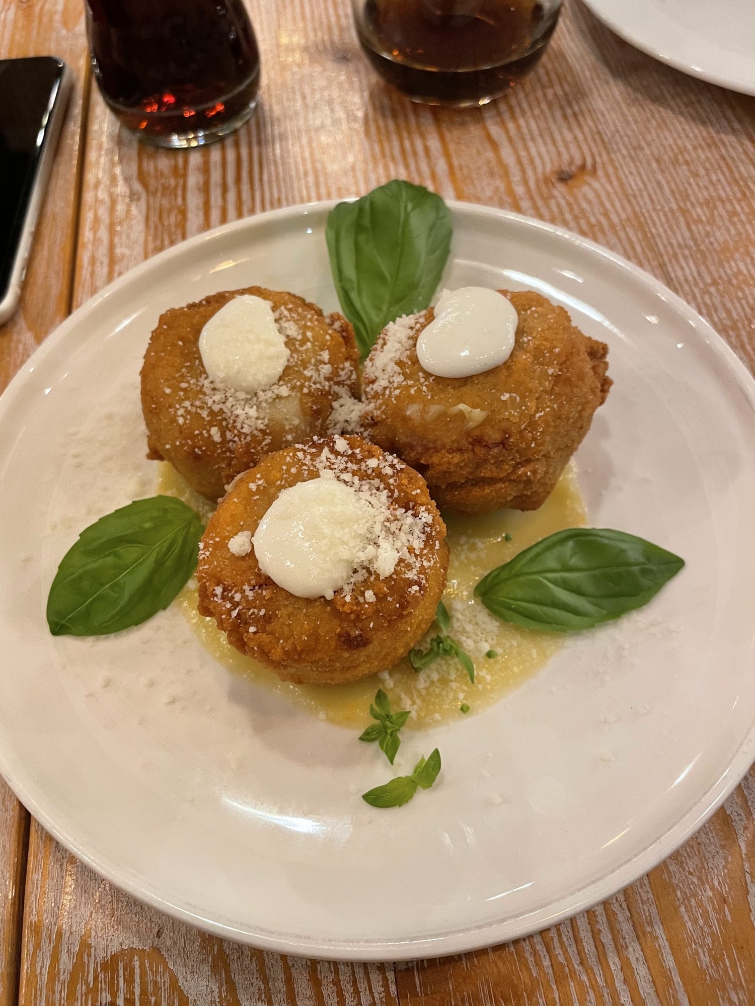 Three fried balls topped with cream and basil
