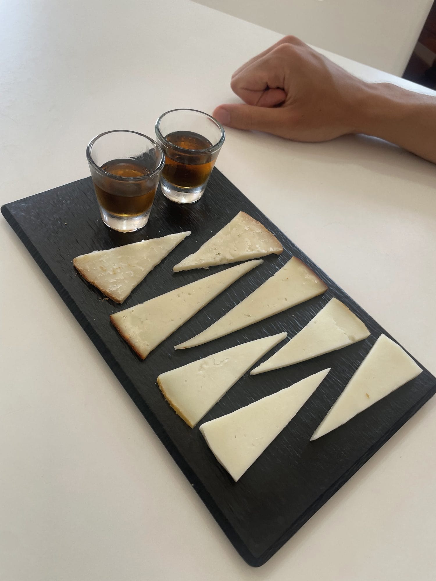 A cheese tasting board with two small glasses